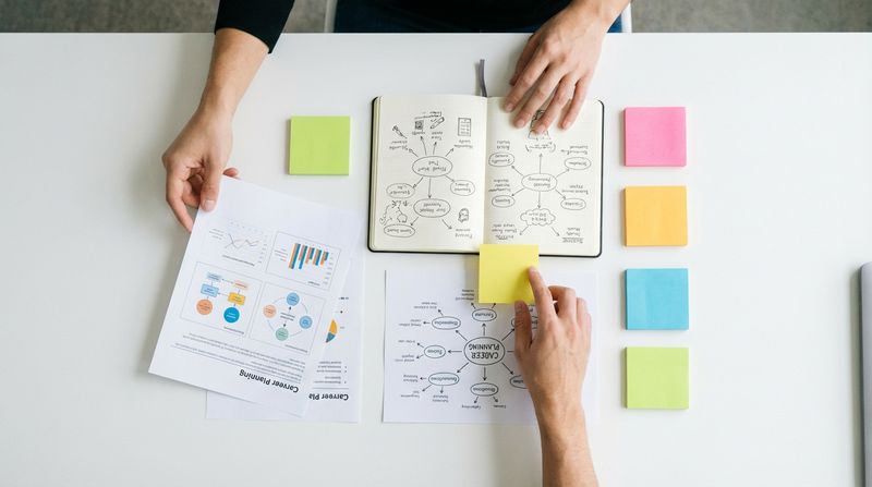 Top-down view of career planning notes, sticky notes and notebooks on a white desk