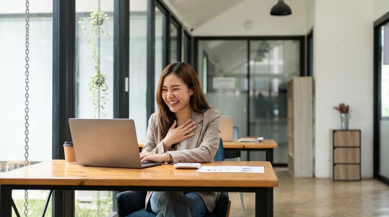 Happy professional receiving exciting news on a laptop in a bright workspace